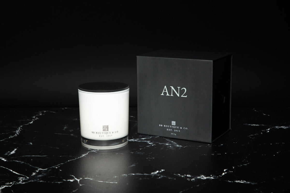 Elegant luxury candle in a glass jar with a clean, minimalist label, softly glowing on a marble surface