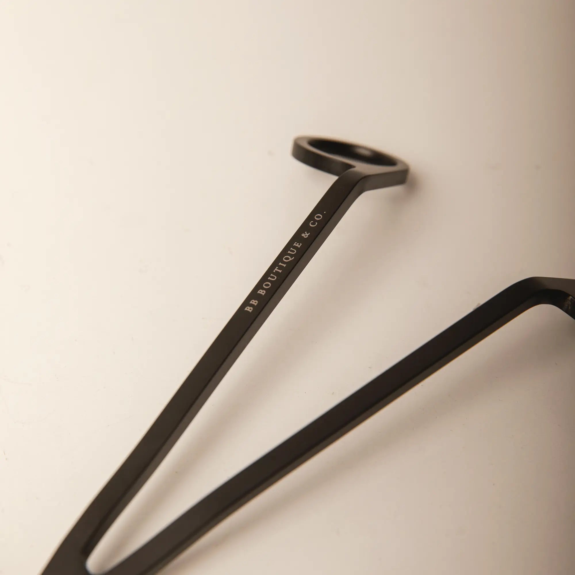 Product photograph of an elegant matte black metal candle wick trimmer featuring 'BB BOUTIQUE & CO.' branding on the handle against a clean light background